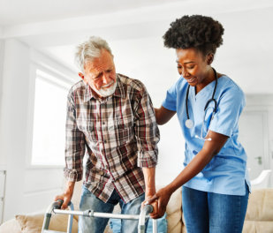 Doctor or nurse caregiver with senior man using walker assistance