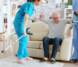 Team of nurses or social workers helping an senior man to walk with his crutches out